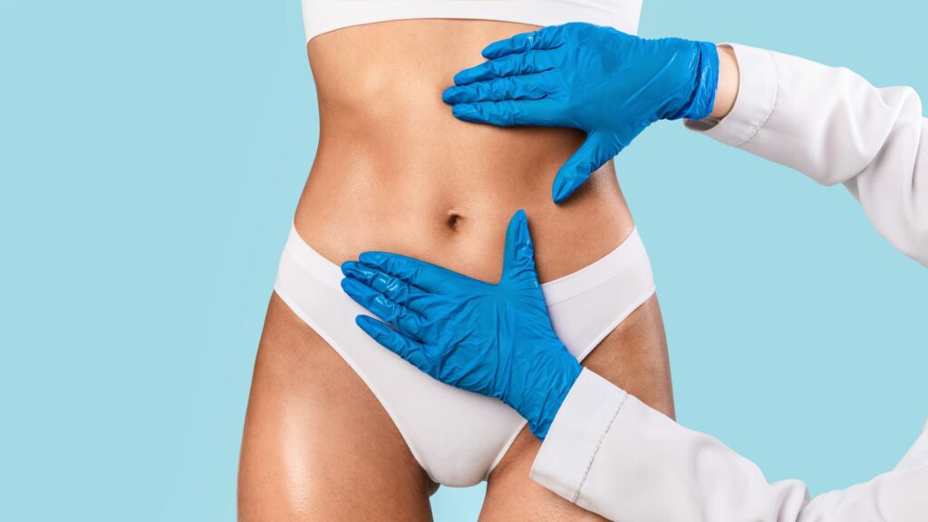 Woman having lipolysis treatment at beauty salon, doctor examining belly